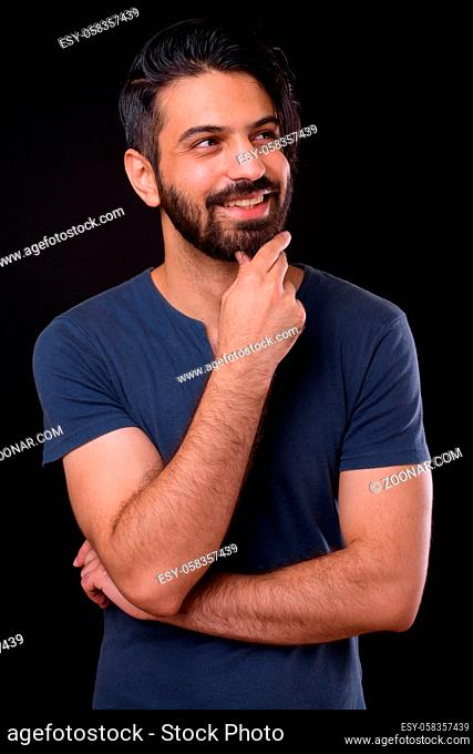 Studio shot of handsome bearded Persian man against black background