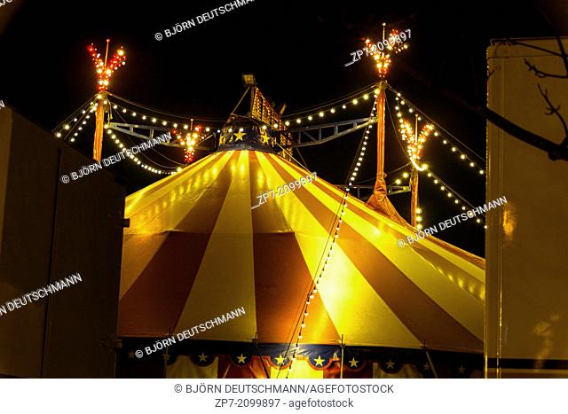 An illuminated big top at night with the nigh sky at background