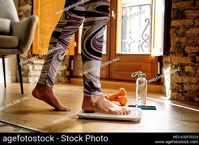 Woman checking weight while standing on weight scale at home