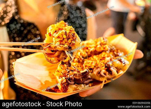 woman eat famous taiwanese snacks of octopus balls at a night marketplace in Taiwan, Asia