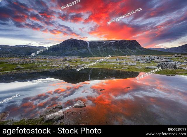 Mountain range reflected in the lake in evening mood with red clouds, Gällivare, Norrbottens län, Sweden, Europe