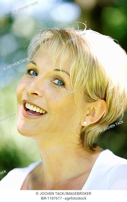 Portrait of a woman, early 40s, in the garden, looking at the camera, smiling