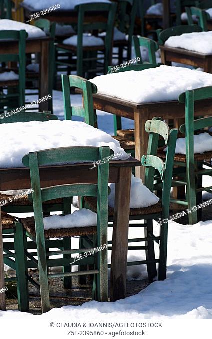 Snow covered tables and chairs in Greek taverna