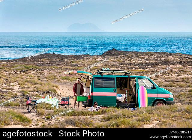 Man and woman spending time in leisure while having camping van trip on shoreline of Lanzarote island, Spain