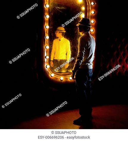 fashionable young man looks at itself in mirror