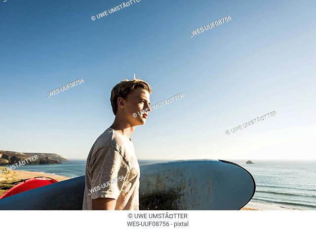 Teenage boy with surfboard looking to the sea