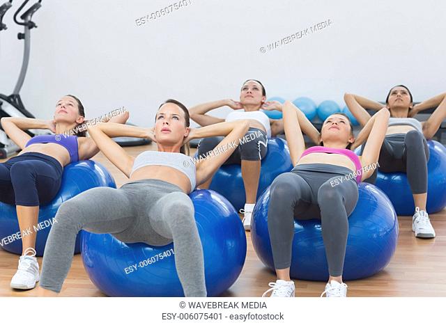 Class doing abdominal crunches on fitness balls