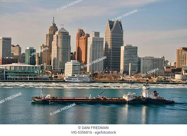 A large bulk carrier cargo ship travels along the Detroit River with the skyline of downtown Detroit, Michigan, USA in the background