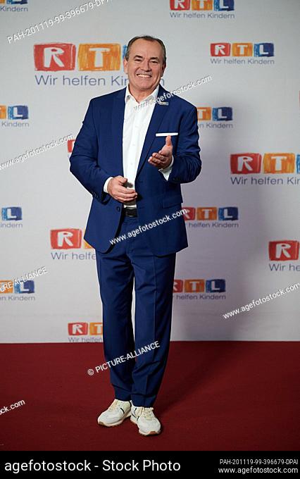19 November 2020, North Rhine-Westphalia, Hürth: The presenter Wolfram Konz sits in front of a photo wall at the 25th RTL Spendenmarathon