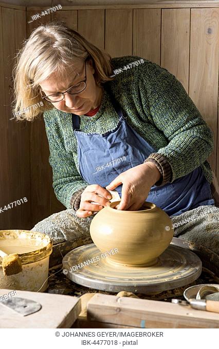 Ceramic workshop, woman working clay with rib on pottery wheel, Pittenhart, Upper Bavaria, Germany