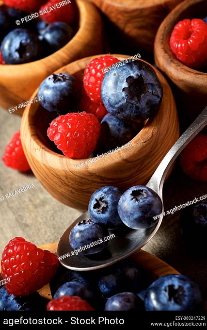 Raspberries and blueberries in wooden bowls