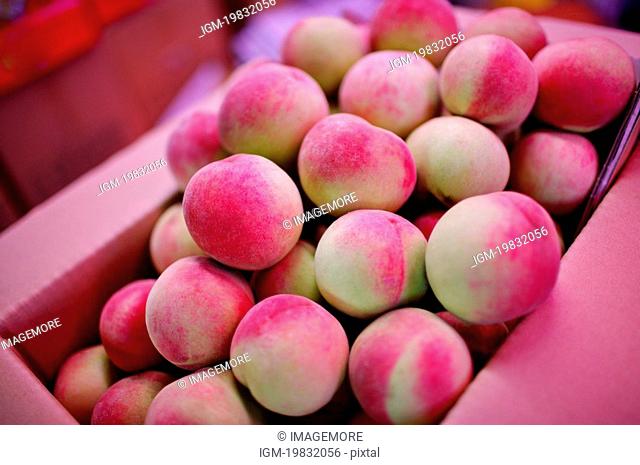 Fresh pale pink peaches in a box, on display