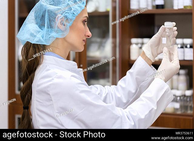 Low-angle side view of a female chemist happy for finding the perfect chemical substance during experimental work in the laboratory of a cosmetics factory