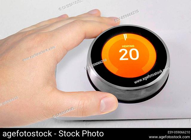 A person adjusting the temperature on a smart thermostat during winter