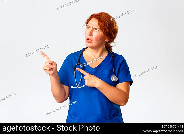 Medicine, healthcare and coronavirus concept. Confused and puzzled middle-aged redhead nurse, doctor cant understand what happening