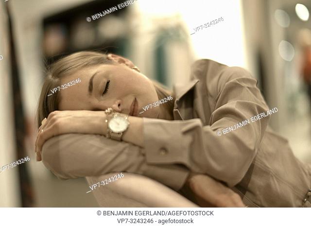 exhausted fashionable woman leaning on armchair, sleepy, closed eyes, tired, relaxing, in Munich, Germany
