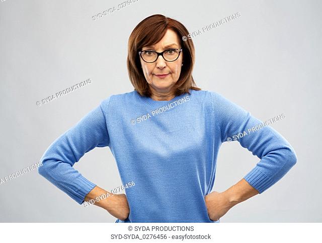 angry senior woman in glasses over grey background