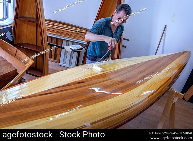 19 May 2022, Mecklenburg-Western Pomerania, Peenemünde: Ulrich Stenberger from Raubling near Rosenheim paints his canoe two-seater