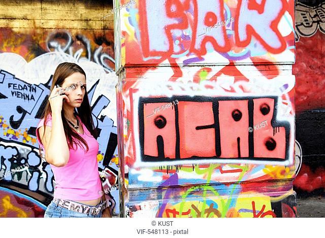 junge Frau telefoniert vor Graffitiwand. - Austria, 25/07/2007