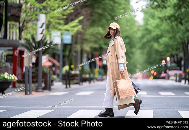 Young woman with shopping bags walking on road