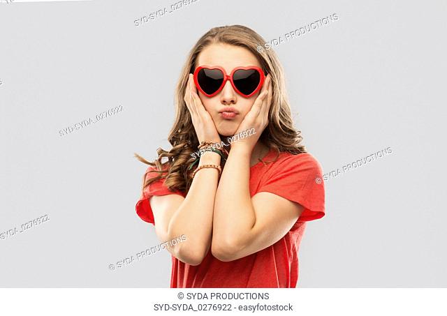 girl in red heart shaped sunglasses pouting