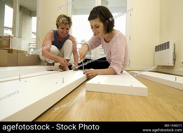 Two women assembling a shelf