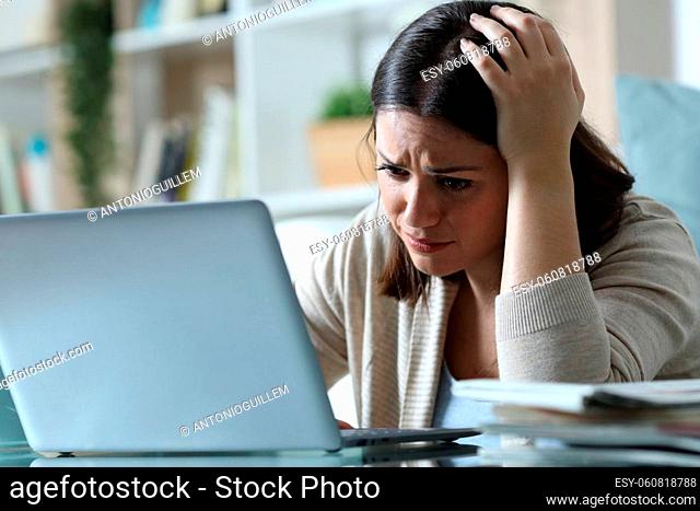 Sad woman complaining checking bad news on email email on a laptop at home