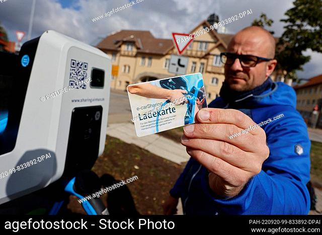 20 September 2022, Saxony-Anhalt, Wernigerode: Lars Bollmann from the Wernigerode municipal utility holds a charging card to an electric car