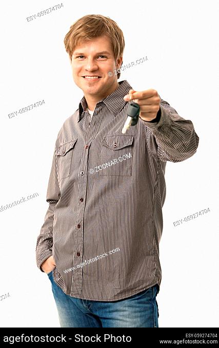 Casual young man holding ignition keys, smiling. Isolated on white