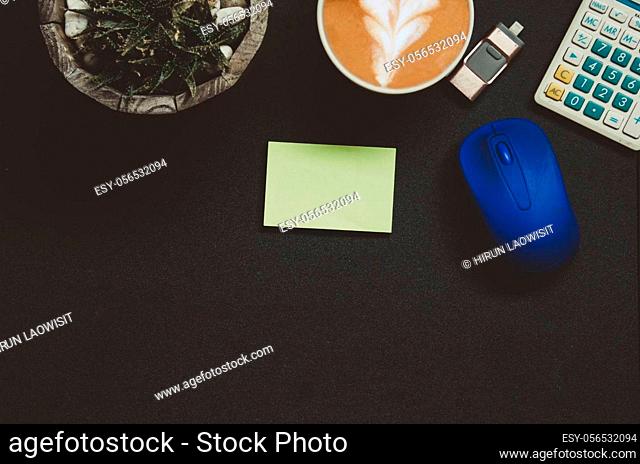 Modern dark office desk table with Office supplies Notepad , .Calculator , coffee , tree , pen and mouse on top view and copy space