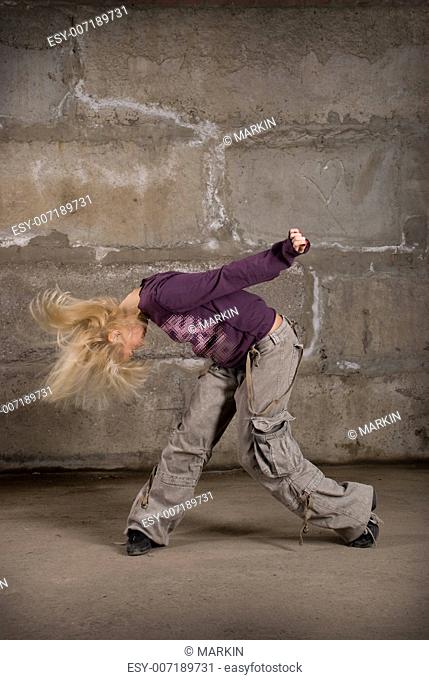 Beautiful hip hop girl dancing over grey brick wall
