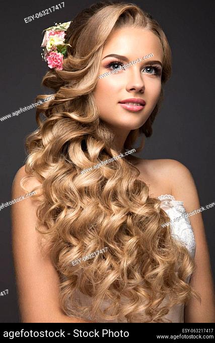 Portrait of a beautiful blond woman in the image of the bride with flowers in her hair. Picture taken in the studio on a black background