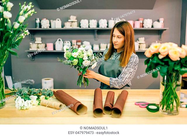 Female florist decorate fresh flower composition. Floral business, bouquet preparation process, materials and tools for decoration on the table