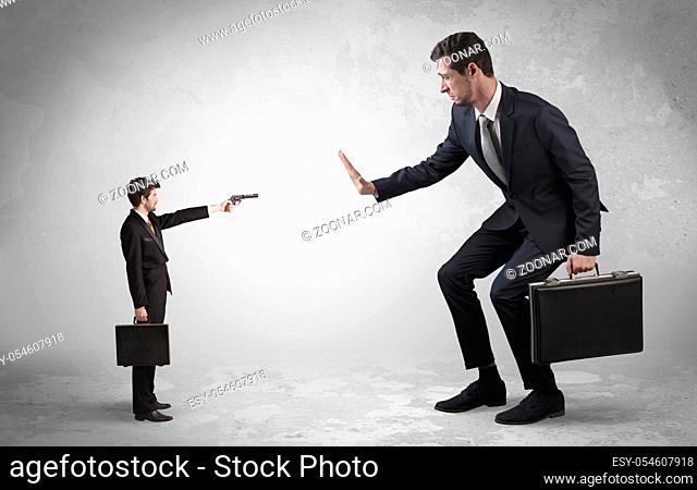 Tiny businessman with gun shooting giant fearful businessman