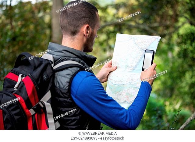 Male hiker looking at map and mobile phone