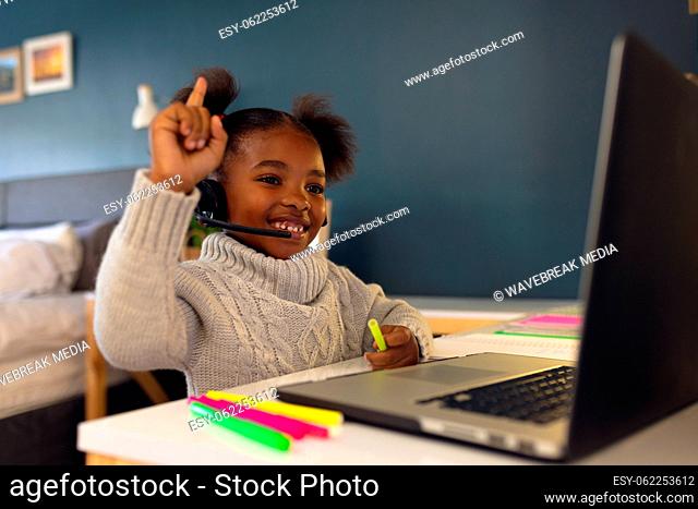 Happy african american girl learning, using laptop and headphone at home