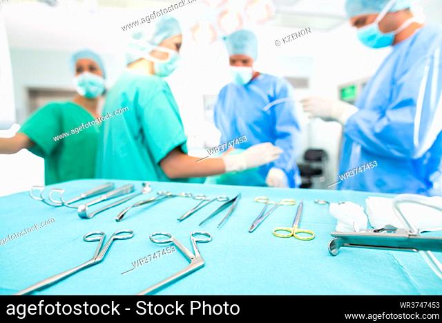 Hospital - surgery team in the operating room or Op of a clinic operating on a patient, perhaps it's an emergency a assistant holding a cotton swap forceps