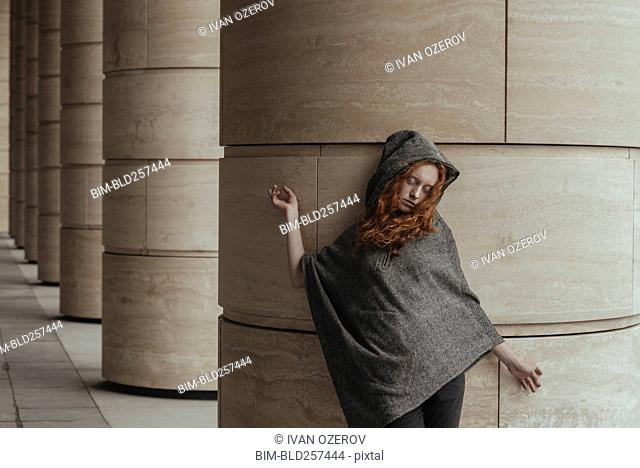 Mujer caucásica despreocupada recostada sobre pilar