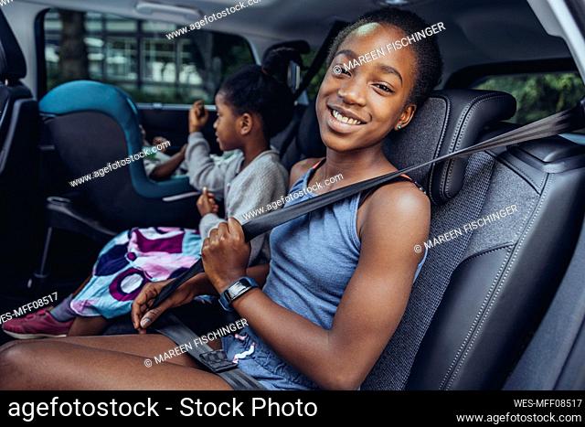 Smiling girl sitting with sister in car