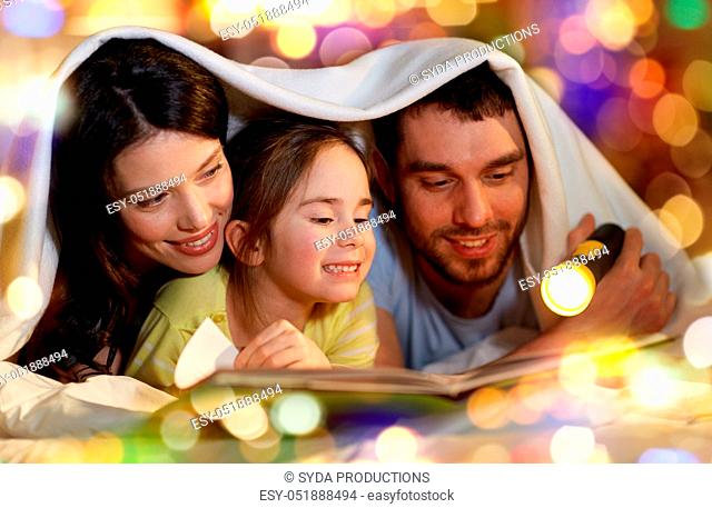 happy family reading book in bed at night at home