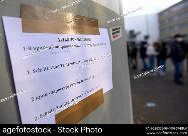 06 March 2022, Hamburg: ""1st step: To the test center in house No. 72"" is written on a piece of paper next to waiting refugees at the arrival center Rahlstedt...
