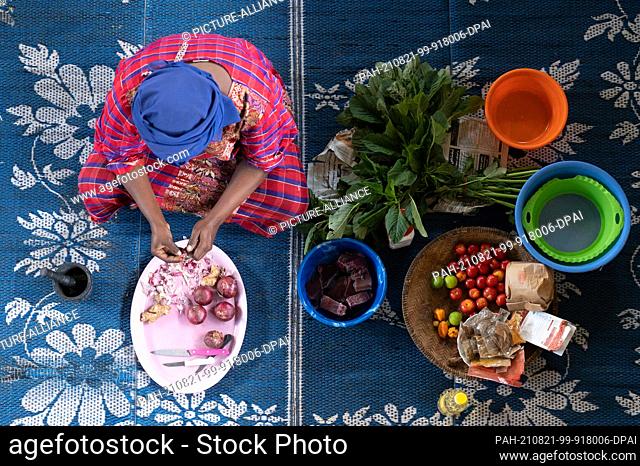 03 August 2021, Tanzania, Sansibar: A woman sits on the floor peeling garlic. Photo: Sebastian Kahnert/dpa-Zentralbild/dpa