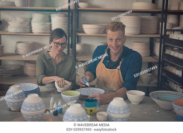 Male and female potter decorating bowl