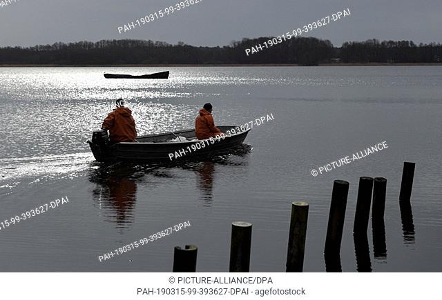 15 March 2019, Brandenburg, Storkow: Two fishermen of the fishery Köllnitz go with a boat on the Groß Schauener lake chain to expose young glass eels