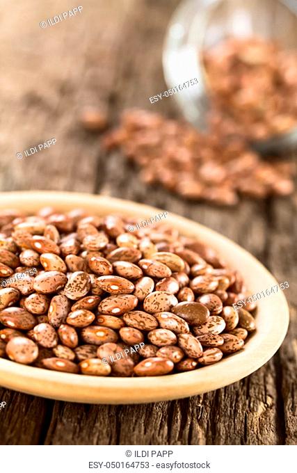 Raw dried pinto beans on wooden plate (Selective Focus, Focus one third into the beans)