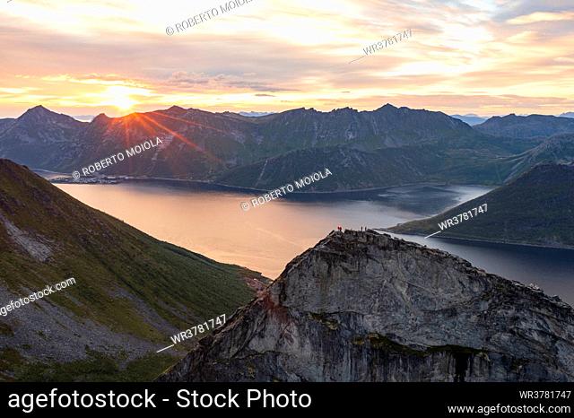 People admiring the sky at dawn standing on mountain top above the fjords, Senja island, Troms county, Norway, Scandinavia, Europe