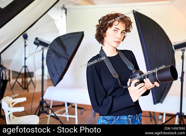 Junge Frau als selbständige Fotografin mit digitaler Kamera im Fotostudio