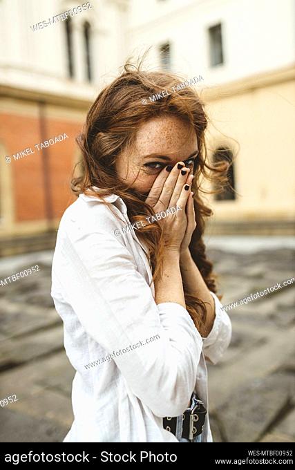 Young woman staring while covering mouth with hands