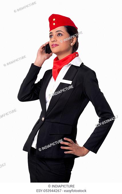 Young airhostess using cell phone while looking up isolated over white background