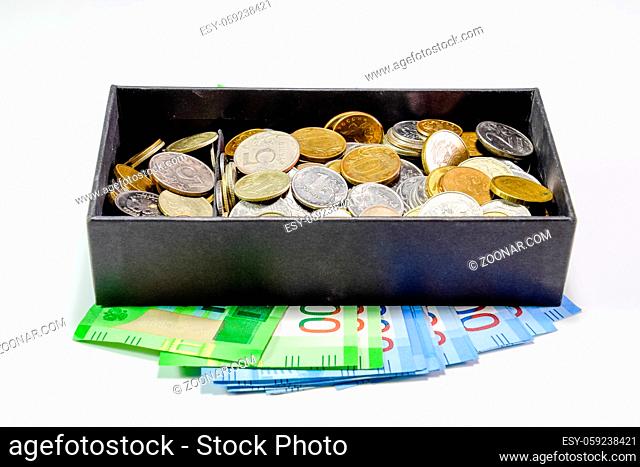 Coins of different denominations in a piggy bank box. Paper rubles under the piggy bank. New banknotes of Russia